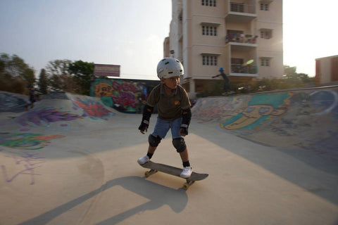 A kid rides a skateboard in a skatepark.