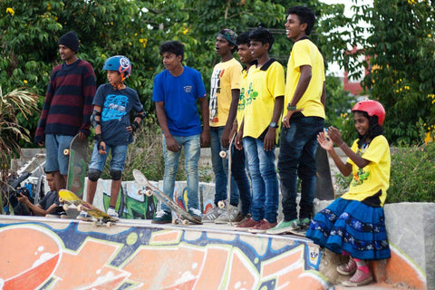 A group of kids stand on a skateboard half pipe.